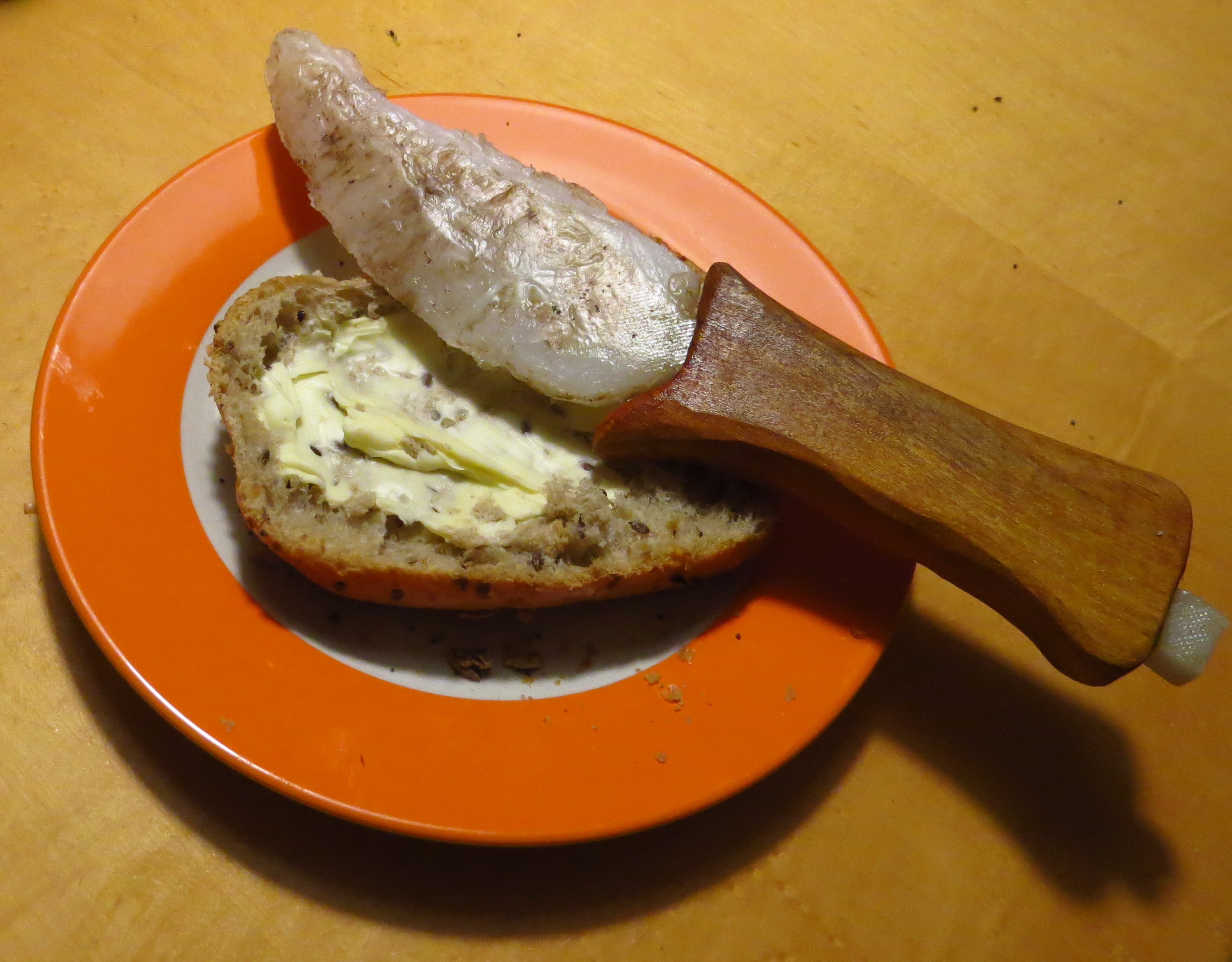 A plastic knife modelling in front of a buttered bun.